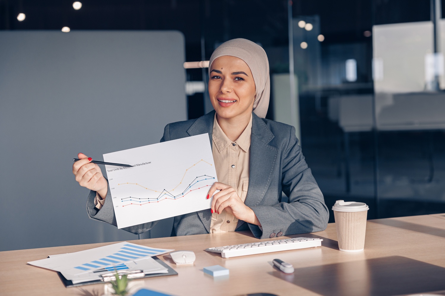 smiling muslim businesswoman in hijab shows a grap amh74w7